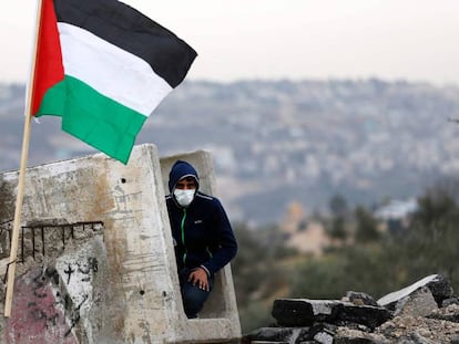 Manifestante palestino se refugia em um bloco de concreto.