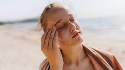 Una chica echándose crema en la cara.