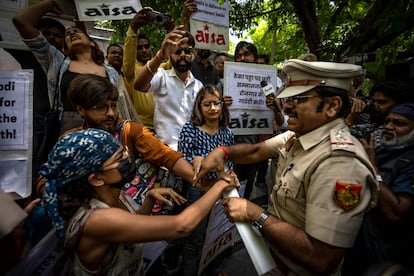 Un oficial de policía arrebata este viernes las pancartas a los estudiantes durante una manifestación en Nueva Delhi, la India.