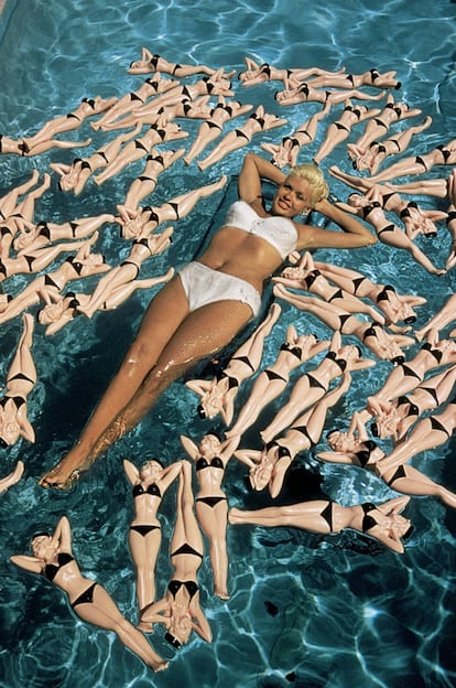 Jayne Mansfield flota en una piscina de California en 1957. Eso que la rodean no son muñecas de sí misma, no, es todavía mejor: son botellas con su forma.