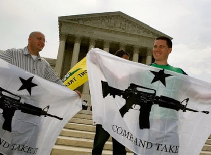 Dos personas se manifiestan a favor del derecho a la posesión de armas ante la Corte Suprema de EE UU, en Washington, con el dibujo de un arma y la inscripción "Ven y cógela".