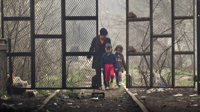 Una mujer y dos ni&ntilde;os entran en un hangar donde se han instalado los refugiados en Idomeni, Grecia.
 