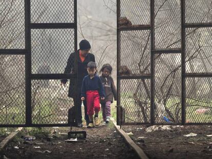 Una mujer y dos niños entran en un hangar donde se han instalado los refugiados en Idomeni, Grecia.