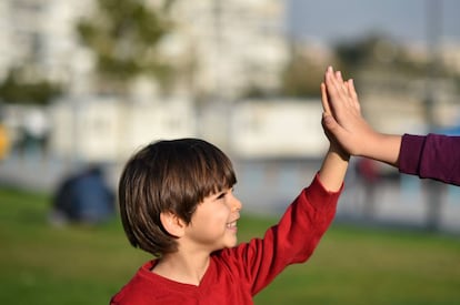Un niño choca la mano con otro chaval.