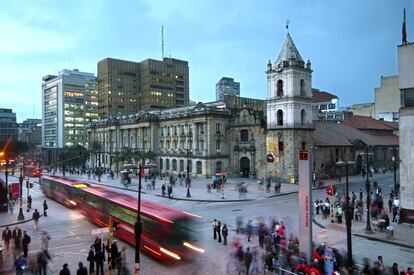 El palacio de San Francisco de Bogot&aacute;  con un autob&uacute;s pasando por delante y mucha gente transitando. 