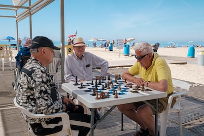 Tres hombres juegan al ajedrez a la sombra en la playa de Levante de Benidorm (Alicante), este domingo.
