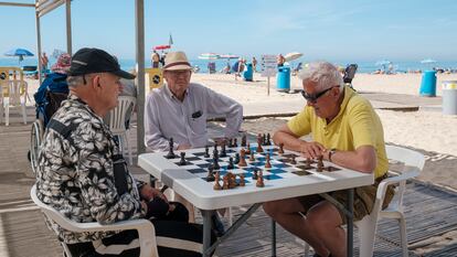Tres hombres juegan al ajedrez a la sombra en la playa de Levante de Benidorm (Alicante), este domingo.
