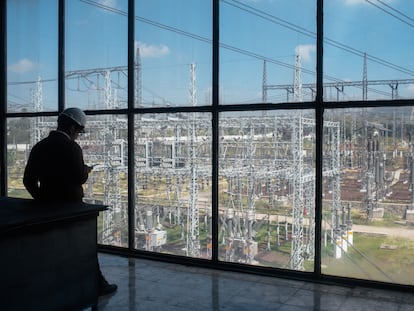 Un trabajador mira un dispositivo móvil frente a la subestación eléctrica de la Comisión Federal de Electricidad en Acolman, Estado de México.