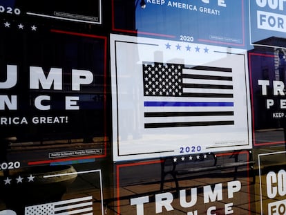 A "Thin Blue Line" sign is surrounded by other signs supporting then-president Donald Trump on the windows of the Racine County Republican Party Office in Racine, Wisconsin, in 2020.