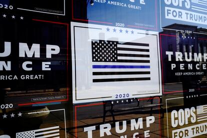 A "Thin Blue Line" sign is surrounded by other signs supporting then-president Donald Trump on the windows of the Racine County Republican Party Office in Racine, Wisconsin, in 2020.