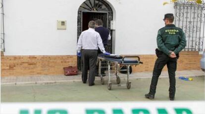 Miembros de los servicios funerarios frente al portal de la mujer hallada muerta en su vivienda.