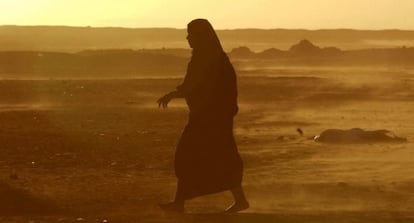 Una mujer camina por el desierto en medio de una tormenta.
