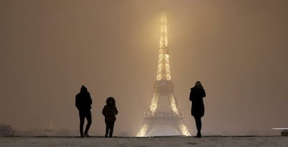 Turistas caminan sobre la nieve cerca de la Torre Eiffel en París.