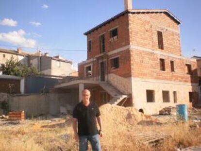 El alcalde de Olmeda de la Cuesta (Cuenca), José Luis Regacho, posa delante de una de las parcelas subastadas en la que su nuevo dueño ya se está construyendo una vivienda.