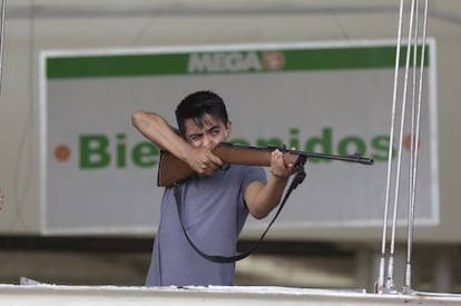 Un empleado de un supermercado impide con un rifle los saqueos.