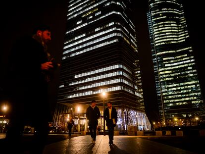 Two young people walk in front of the area of the four business towers in Madrid, Spain.