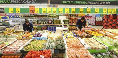 Dos empleados reponen mercanc&iacute;a en la fruter&iacute;a de un Lidl de Madrid. 