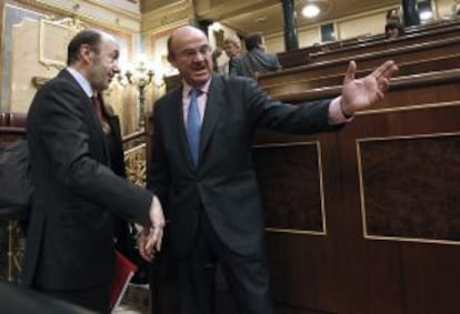 Guindos charla con Rubalcaba a su llegada al Congreso.