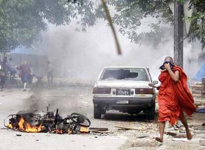 Un monje budista pasa junto a una motocicleta incendiada tras los incidentes ocurridos ayer en Yangon, en una foto divulgada por la Liga Nacional para la Democracia de Suu Kyi.