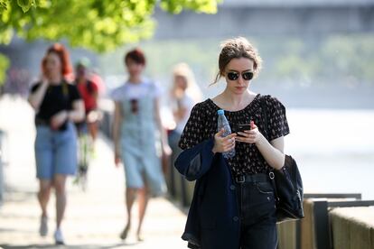 Mulher consulta telefone celular enquanto passeia em Moscou.