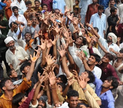 Un grupo de paquistaníes piden agua a los militares que la distribuyen.