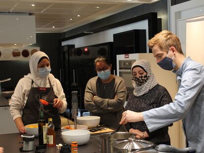 El chef Sebastian Simon prepara recetas con tres mujeres solicitantes de asilo en un taller organizado desde la ONG Accem en torno a las personas refugiadas y la cocina sostenible en Madrid.