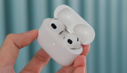 Auriculares AirPods de Apple sujetados con la mano