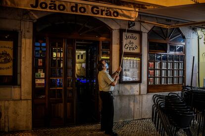 Un camarero cierra las persianas de un restaurante en el centro de Lisboa el 9 de noviembre de 2020.