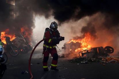 Un bombero trabaja junto a varios vehículos incendiados durante la protesta de los 'chalecos amarillos' por el centro de París.