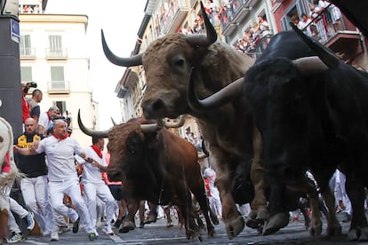 Los toros de la ganadería Jandilla persiguen a los mozos a su paso por la curva de Mercaderes.
