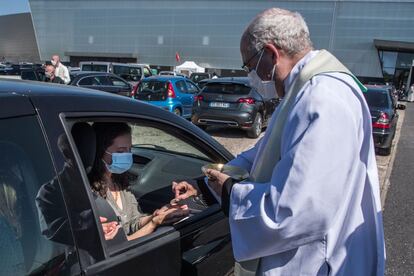 Un sacerdote da la comunión a los fieles durante la celebración de la primera misa en automóvil en Chalons-en-Champagne (Francia).