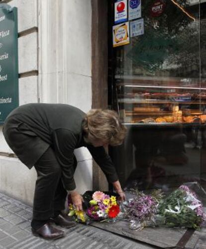 Una mujer deposita un ramo de flores en la panadería Bopan tras el asesinato.