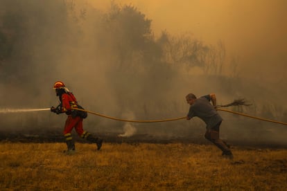 Un efectivo de la UME y un vecino de la localidad apuntan una manguera contra el fuego en Chandrexa de Queixa, en Ourense.