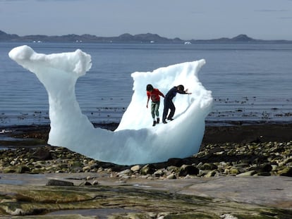 Dos niños juegan con un iceberg en ​​la playa en Nuuk, Groenlandia.