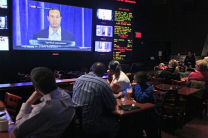 Aficionados siguen por televisión la rueda de prensa de Tiger Woods.