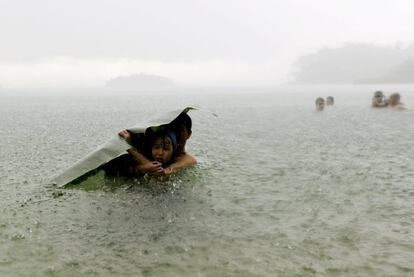 A young girl covers herself from the rain with a banana leaf next to a man in the sea on the outskirts of Colon City, October 17, 2015. REUTERS/Carlos JassoSEARCH "THE NATURAL WORLD" FOR ALL 20 IMAGES