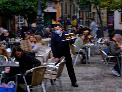 Un camarero sirve una mesa en una terraza de Sevilla.