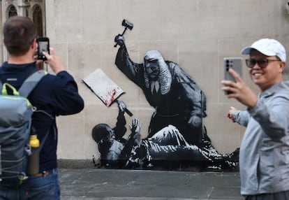 Transeúntes hacen fotografías del mural de Banksy el lunes, en el Tribunal Superior de Justicia de Londres.