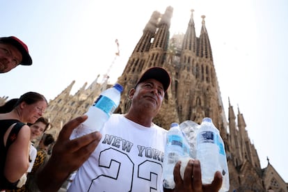 Un hombre vende botellas de agua a los turistas junto a la basílica de la Sagrada Familia en Barcelona, este martes.