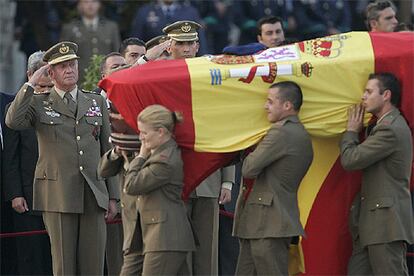 El Rey y el Prncipe saludan al paso de un atad, cubierto con la bandera y coronado con la boina del fallecido.