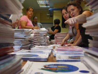 Varias madres preparan lotes de libros de la cooperativa escolar del colegio p&uacute;blico Asturias, en Madrid.
