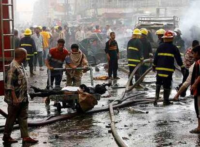 Residentes y equipos de rescate en el lugar de uno de los atentados con coche bomba cometidos ayer en Bagdad.