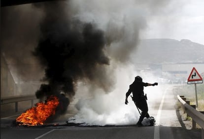 Un agente intenta eliminar una de las barreras de neumáticos ardiendo en Andorra (Teruel).