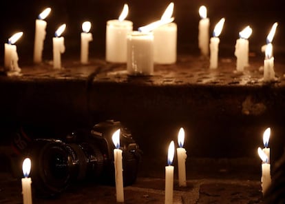 Velas encendidas en torno a una cámara en la vigilia en homenaje a los periodistas asesinados.
