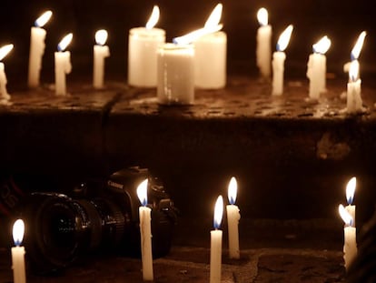 Velas encendidas en torno a una cámara en la vigilia en homenaje a los periodistas asesinados.