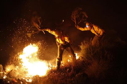 Los bomberos tratan de extinguir un fuego con ramas en Barranco Blanco, en Coín.
