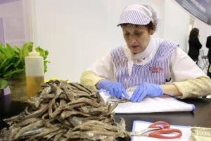 Una mujer limpia anchoas en el estand de Cantabria que hoy celebra el Día de la Comunidad en la Feria internacional de Turismo (Fitur) que tiene lugar en Madrid.