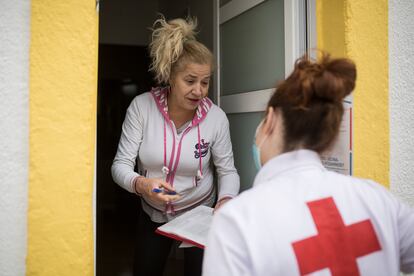 Cristina, voluntaria de Cruz Roja, reparte un lote a Yoslen Garrido, en el barrio de Nou Barris.