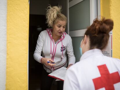 Cristina, voluntaria de Cruz Roja, reparte un lote a Yoslen Garrido, en el barrio de Nou Barris.