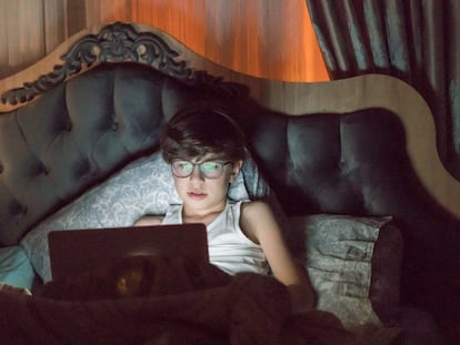 Un niño usa un portátil en la cama.